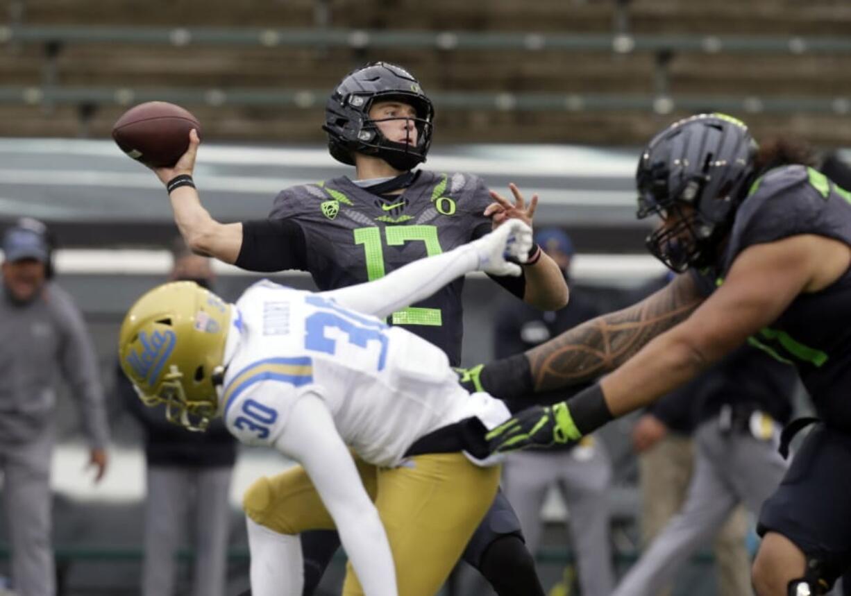 Oregon&#039;s Tyler Shough throws down field under pressure from UCLA&#039;s Elisha Guidry during the second quarter of an NCAA college football game Saturday, Nov. 21, 2020, in Eugene, Ore.