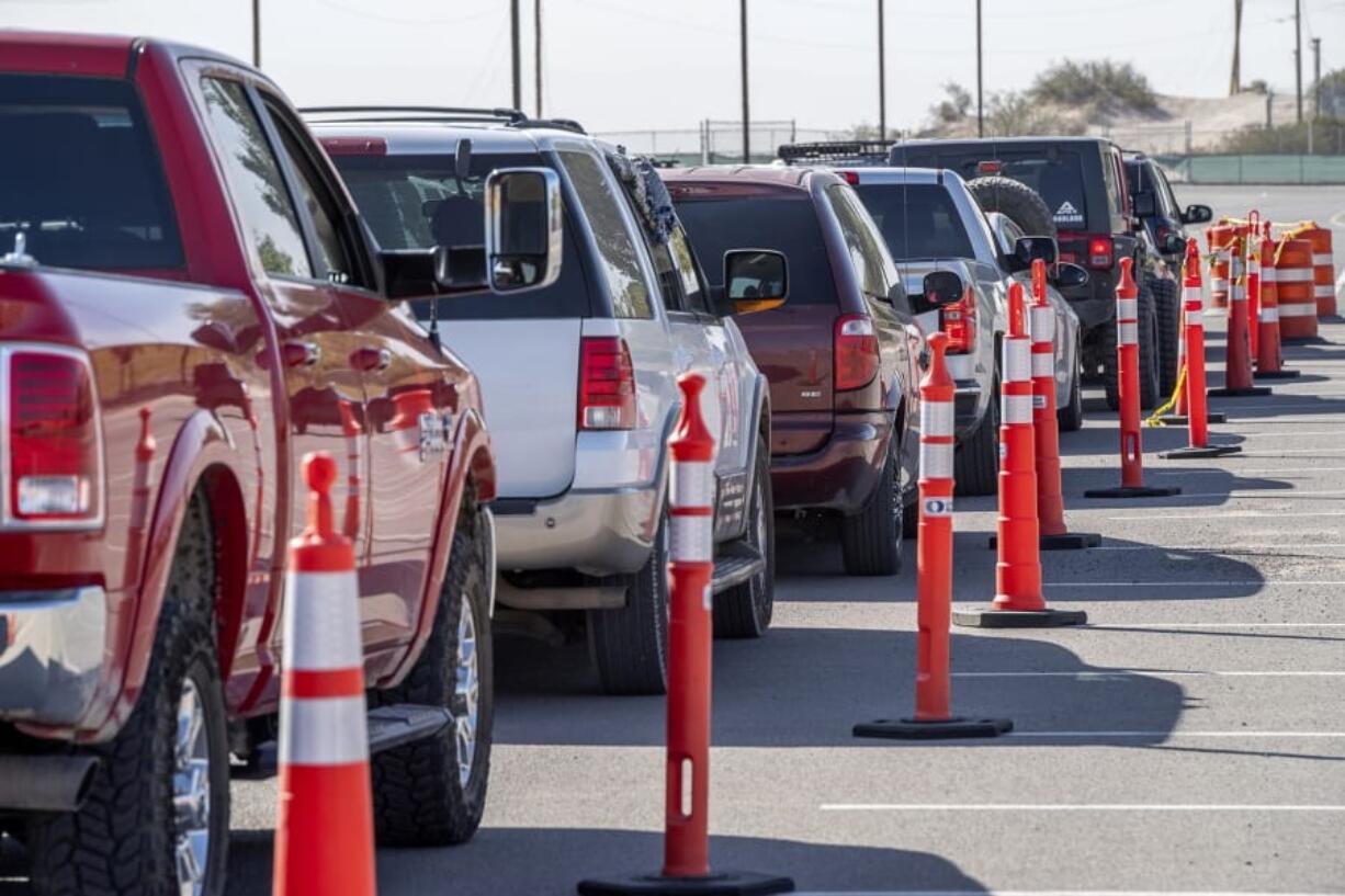 FILE - In this Oct. 14, 2020, file photo, vehicles are lined up for drive-thru COVID-19 testing in El Paso, Texas. As the coronavirus pandemic surges across the nation and infections and hospitalizations rise, medical administrators are scrambling to find enough nursing help -- especially in rural areas and at small hospitals. (Aaron E.