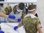 Soldiers carry out mass coronavirus testing, set up at a marketplace in Liverpool, England, during the four-week national lockdown to curb the spread of coronavirus in England, Wednesday Nov. 11, 2020.