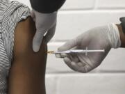 FILE - In this Wednesday, June 24, 2020 file photo, a volunteer receives an injection at the Chris Hani Baragwanath hospital in Soweto, Johannesburg, as part of Africa&#039;s first participation in a COVID-19 vaccine trial developed at the University of Oxford in Britain in conjunction with the pharmaceutical company AstraZeneca. AstraZeneca says late-stage trials of its COVID-19 vaccine were &quot;highly effective&#039;&#039; in preventing disease. A vaccine developed by AstraZeneca and the University of Oxford prevented 70% of people from developing the coronavirus in late-stage trials, the team reported Monday Nov. 23, 2020.