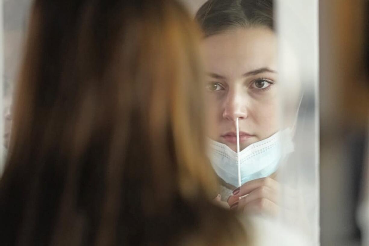 FILE -- In this Nov. 18, 2020, file photo, University of Utah student Abigail Shull takes a rapid COVID-19 test in Salt Lake City. As coronavirus cases are surging around the U.S., some colleges and universities are rethinking some of their plans for next semester.