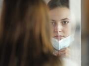 FILE -- In this Nov. 18, 2020, file photo, University of Utah student Abigail Shull takes a rapid COVID-19 test in Salt Lake City. As coronavirus cases are surging around the U.S., some colleges and universities are rethinking some of their plans for next semester.