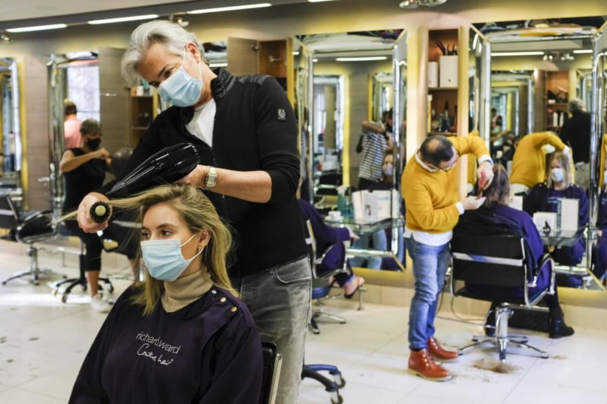 In this Wednesday, Nov. 4, 2020 file photo, Richard Ward, owner of Richard Ward Hair &amp; MetroSpa wears a protective face mask as he works in his salon in London. Britain is preparing to join large swathes of Europe in a coronavirus lockdown designed to save its health care system from being overwhelmed. Pubs, along with restaurants, hairdressers and shops selling non-essential items will have to close Thursday until at least Dec. 2.