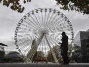 A man passes a closed Ferris wheel in the city center of Essen, Germany, Monday, Nov. 2, 2020. A one month long partial lockdown due to the coronavirus pandemic becomes effective in Germany on Monday.