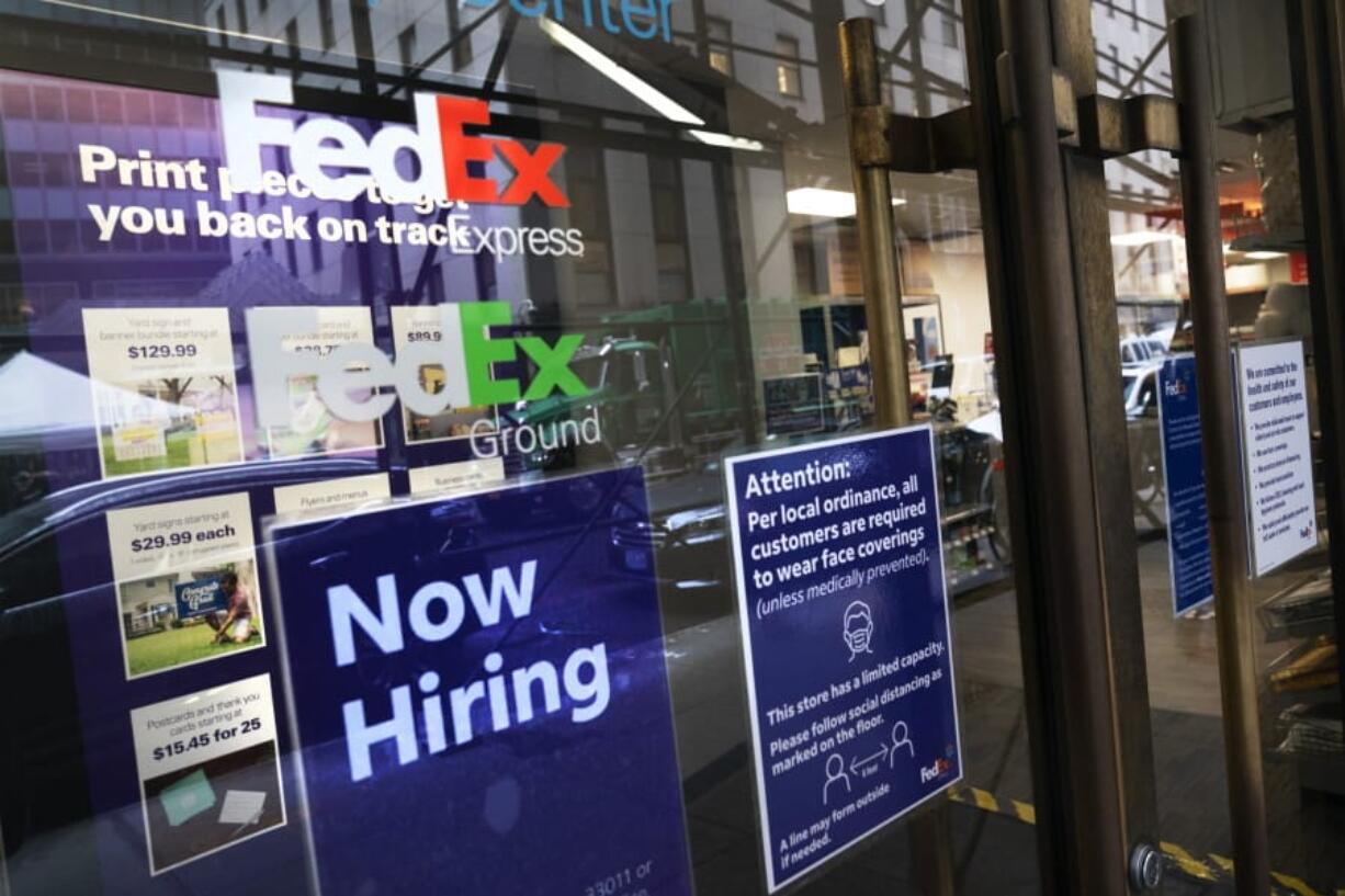 A sign in the window of a FedEx office reads, &quot;Now Hiring,&quot; Monday, Oct. 26, 2020 in New York.  Carriers like FedEx and UPS are ramping up their holiday hiring while asking store clients to move their shipping volume on lighter days in their network.