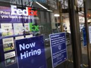 A sign in the window of a FedEx office reads, &quot;Now Hiring,&quot; Monday, Oct. 26, 2020 in New York.  Carriers like FedEx and UPS are ramping up their holiday hiring while asking store clients to move their shipping volume on lighter days in their network.