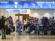 Holiday travelers check in at kiosks near an airline counter at Orlando International Airport Tuesday, Nov. 24, 2020, in Orlando, Fla.