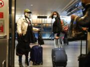 Travelers leave the AirTrain at JKF International Airport Friday, Nov. 20, 2020, in New York. Rising U.S. coronavirus cases, a new round of state lockdowns and public health guidance discouraging trips are dampening enthusiasm for what is usually the biggest travel period of the year.