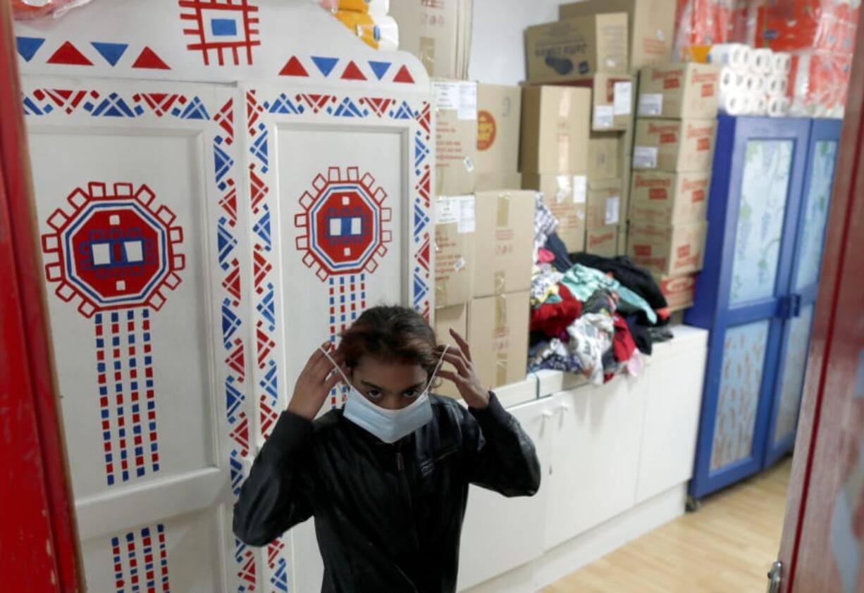 In this photo taken Wednesday, Oct. 28, 2020, a girl puts on her mask in Svratiste, or Roadhouse, Belgrade&#039;s first daily drop-in center for street children, in Serbia. For years, a small house tucked away in a Belgrade residential area has been an oasis of warmth and comfort for the Serbian capital&#039;s most vulnerable inhabitants  - street children. The Roadhouse drop-in center has served the basic needs of hundreds of children who often have nowhere else to wash, warm up or properly eat.