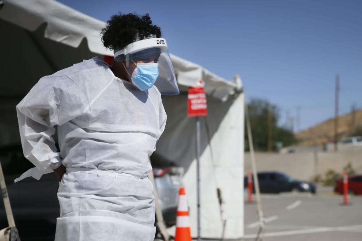 FILE - In this Oct. 26,2020, file photo, a medical worker stands at a COVID-19 state drive-thru testing site at UTEP, in El Paso, Texas. The U.S. has recorded about 10.3 million confirmed infections, with new cases soaring to all-time highs of well over 120,000 per day over the past week.