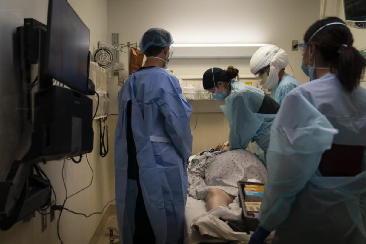 FILE - In this Nov. 19, 2020, file photo, EMT Giselle Dorgalli, third from right, performs chest compression on a patient who tested positive for coronavirus in the emergency room at Providence Holy Cross Medical Center in the Mission Hills section of Los Angeles. (AP Photo/Jae C.