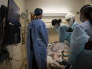 FILE - In this Nov. 19, 2020, file photo, EMT Giselle Dorgalli, third from right, performs chest compression on a patient who tested positive for coronavirus in the emergency room at Providence Holy Cross Medical Center in the Mission Hills section of Los Angeles. (AP Photo/Jae C.