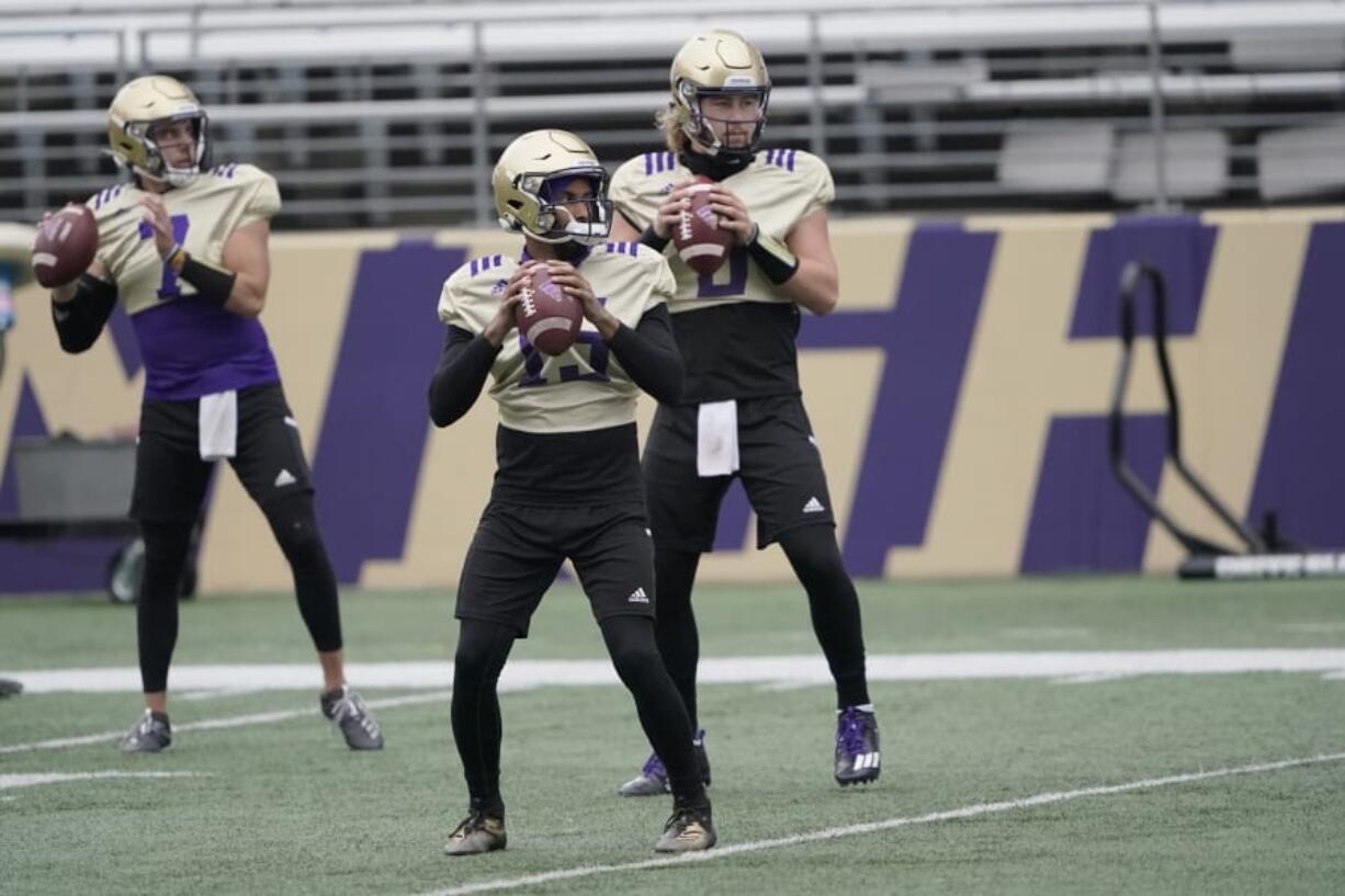 Washington quarterbacks Jaden Sheffey, center, Kevin Thomson, left, and Jacob Sirmon, right, pass in a group during NCAA college football practice, Friday, Oct. 16, 2020, in Seattle. (AP Photo/Ted S. Warren) (Photos by Ted S.