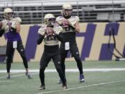 Washington quarterbacks Jaden Sheffey, center, Kevin Thomson, left, and Jacob Sirmon, right, pass in a group during NCAA college football practice, Friday, Oct. 16, 2020, in Seattle. (AP Photo/Ted S. Warren) (Photos by Ted S.