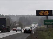 A steady flow of cars move under a sign on I-5 reading, “STAY HOME, LIMIT TRAVEL, SAVE LIVES," in Vancouver on Tuesday, March 24, 2020.