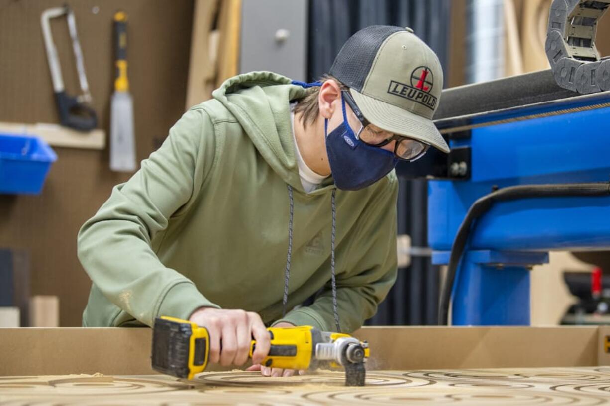 Discovery High School junior Jordan Ruseoliver uses a router to finish up the pieces of the base of a stanchion at the Camas high school. Discovery High engineering students designed and built stanchions for the area schools to help ease traffic flow when schools return to in-person learning. With a part in the process from design to finished product, Discovery students get real-world experience out of a state-of-the-art lab at the school.