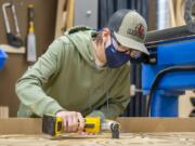 Discovery High School junior Jordan Ruseoliver uses a router to finish up the pieces of the base of a stanchion at the Camas high school. Discovery High engineering students designed and built stanchions for the area schools to help ease traffic flow when schools return to in-person learning. With a part in the process from design to finished product, Discovery students get real-world experience out of a state-of-the-art lab at the school.