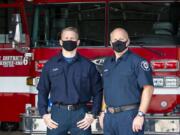 Firefighter and paramedic Max Olson, left, and firefighter and emergency medical technician Dave Fisher pose in front of a fire truck on Dec. 8 at Clark County Fire District 6 Station 61. They responded to the first reported COVID-19 case in the county.