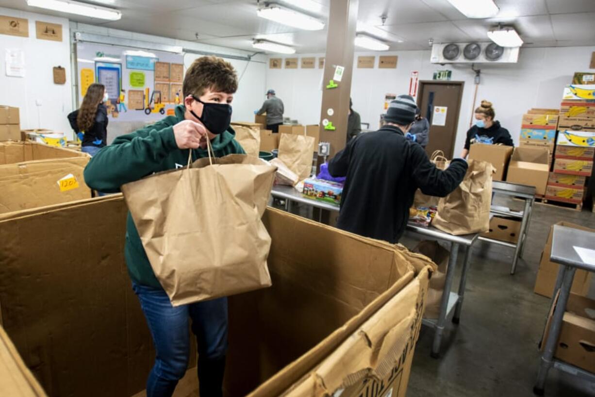 Volunteer Ray Thorne, who has volunteered at the food bank for close to two decades, helps gather food items out of a large box for others to sort on Tuesday at the Clark County Food Bank. The donations were from Saturday's Drive & Drop food drive, which in previous years was known as Walk & Knock.