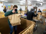 Volunteer Ray Thorne, who has volunteered at the food bank for close to two decades, helps gather food items out of a large box for others to sort on Tuesday at the Clark County Food Bank. The donations were from Saturday's Drive & Drop food drive, which in previous years was known as Walk & Knock.