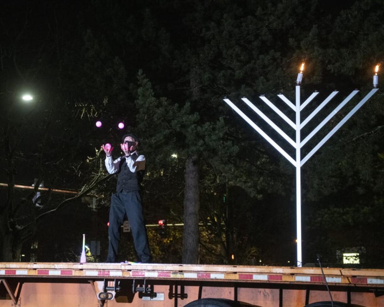 A performer from Circus Luminescence juggles in front of an audience at a drive-in menorah lighting Thursday night in a parking lot across the street from the Clark County Historical Museum.
