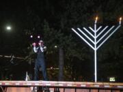 A performer from Circus Luminescence juggles in front of an audience at a drive-in menorah lighting Thursday night in a parking lot across the street from the Clark County Historical Museum.