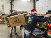 Rod Cook, left, helps load boxed-up bicycle kits into the back of a volunteer&#039;s pickup truck while Hayden Trent, right, repositions other boxes on Saturday morning at Taylor Transport in the Barberton area. Pre-registered volunteers drove though the warehouse to collect new bikes for home assembly. The bikes will be passed along to needy local families at Christmas.