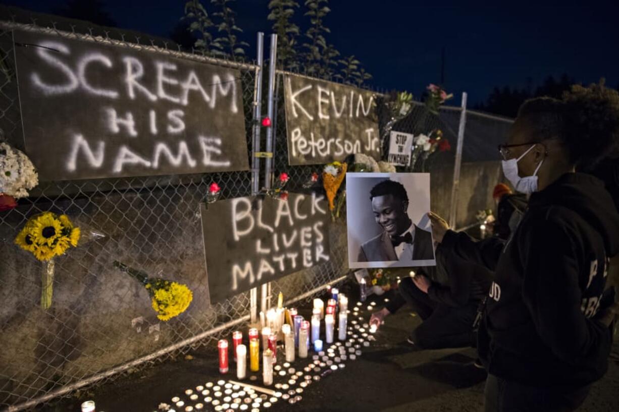 Alisha, who declined to give her last name, holds a photo of Kevin Peterson Jr., a 21-year-old Black Camas man who was shot and killed by law enforcement, as he is remembered with a candlelight vigil at the Hazel Dell branch of U.S. Bank on Oct. 30, 2020. Hundreds of supporters gathered to honor Peterson&#039;s memory at the vigil. Law enforcement tasked with investigating the fatal shooting of Kevin Peterson Jr. say Clark County deputies fired a total of 34 rounds, with four rounds striking him. Three deputies fatally shot Peterson following a planned drug sale of 50 Xanax pills between him and a confidential informant outside a Quality Inn motel in Hazel Dell on the evening of Oct. 29, according to court records.