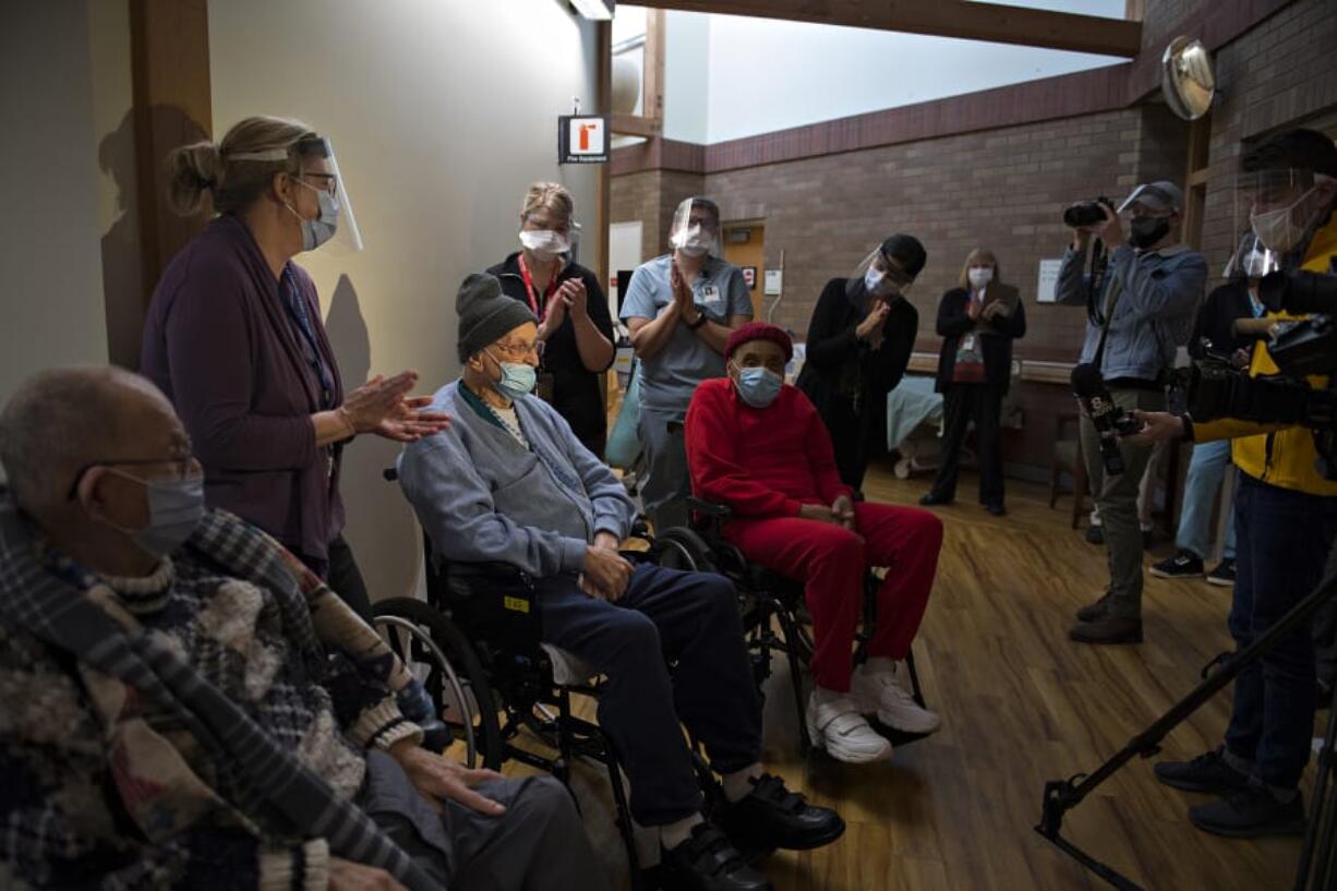 Veterans Lawrence Doyle, from left, John Stephens and James Curry receive a round of applause after getting their COVID-19 vaccinations at the Community Living Center on the Veterans Affairs campus Thursday morning.