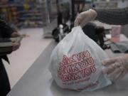 Cashier Razija Zelknovic assists a customer with their plastic bag after making a purchase at the Orchards Goodwill.