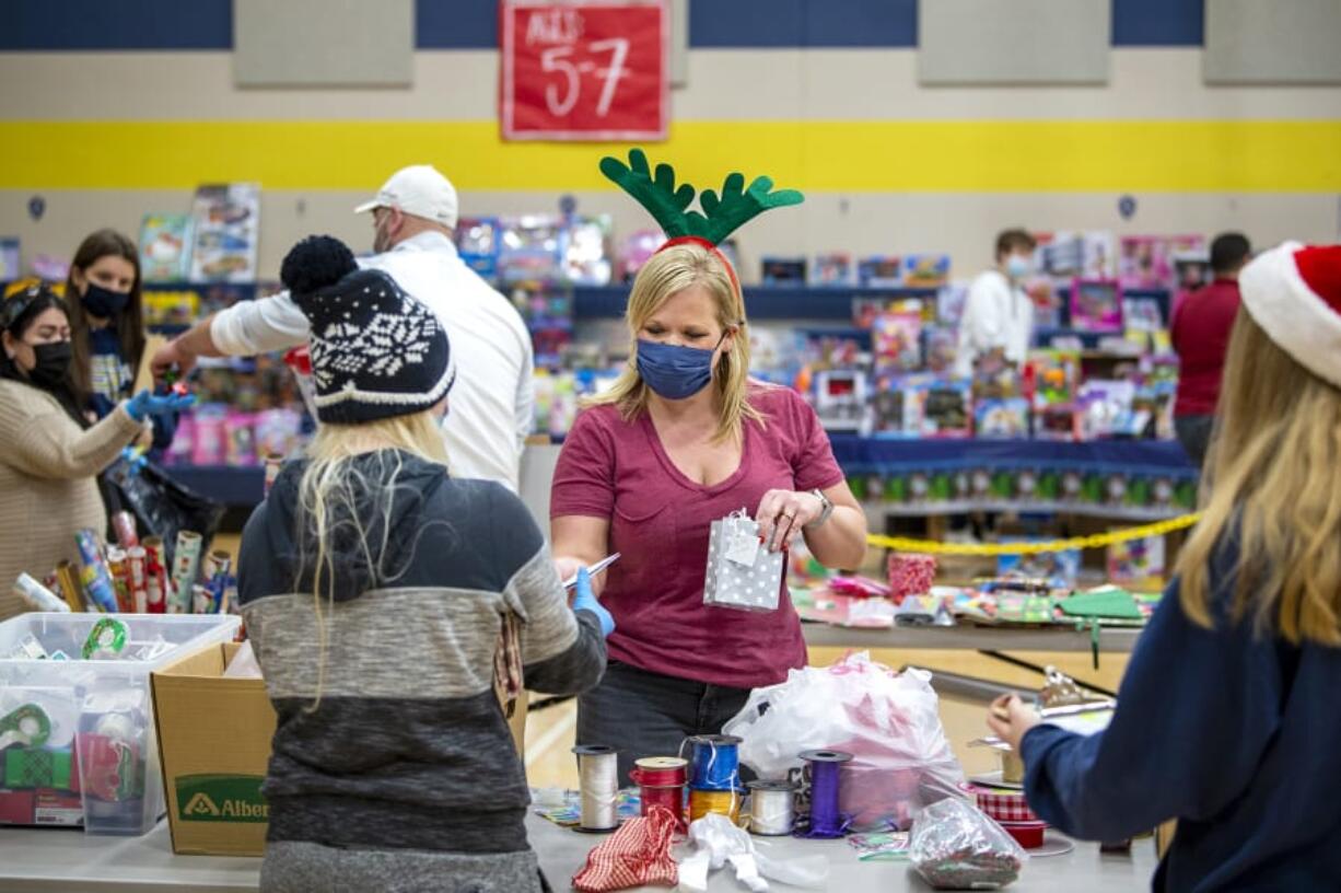 Parent volunteer Joanna Hammerstrom helps shoppers pick out wrapping paper, cards and bows on Saturday, Dec. 19, at Seton Catholic College Prep. The toy drive was put on by St. Vincent De Paul, who used Seton Catholic&#039;s facilities and student and parent volunteers to serve the community.