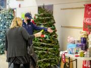 Seton Catholic principal Robert Rusk explains how the Christmas tree raffle works to a toy drive shopper on Saturday, Dec. 19, at Seton Catholic College Prep. Each guest could enter a ticket into one of the Christmas tree boxes. The winner will have the tree delivered.