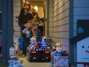 Kevin Hale, background in tan to front, of Longview joins his wife, Lindsay, his daughter, Annabelle, 6, and his son, Sawyer, 4, as they walk out to a porch full of donated gifts on Friday evening. Members of the Vancouver Police Department Domestic Violence Unit delivered the gifts to the family. Kevin Hale has been diagnosed with Stage 4 endocrine cancer, and his wife, Lindsay, works for the Clark County Prosecuting Attorney's Office as a victim advocate with the domestic violence unit.