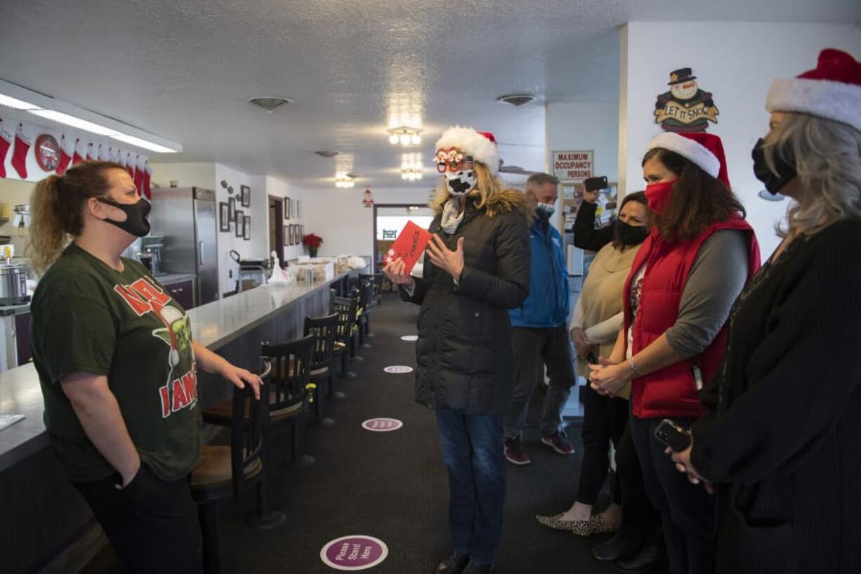 Shannon Holliday, manager at Carol&#039;s Corner Cafe, left, chats with Kathryn Tilkin of Hockinson, center, as the restaurant receives a generous holiday tip from Tilkin and her friends on Dec. 18. The group picked up a to-go order of 25 cinnamon rolls and left a holiday card with $3,100 to support the restaurant, which has been struggling due to COVID-19 restrictions.