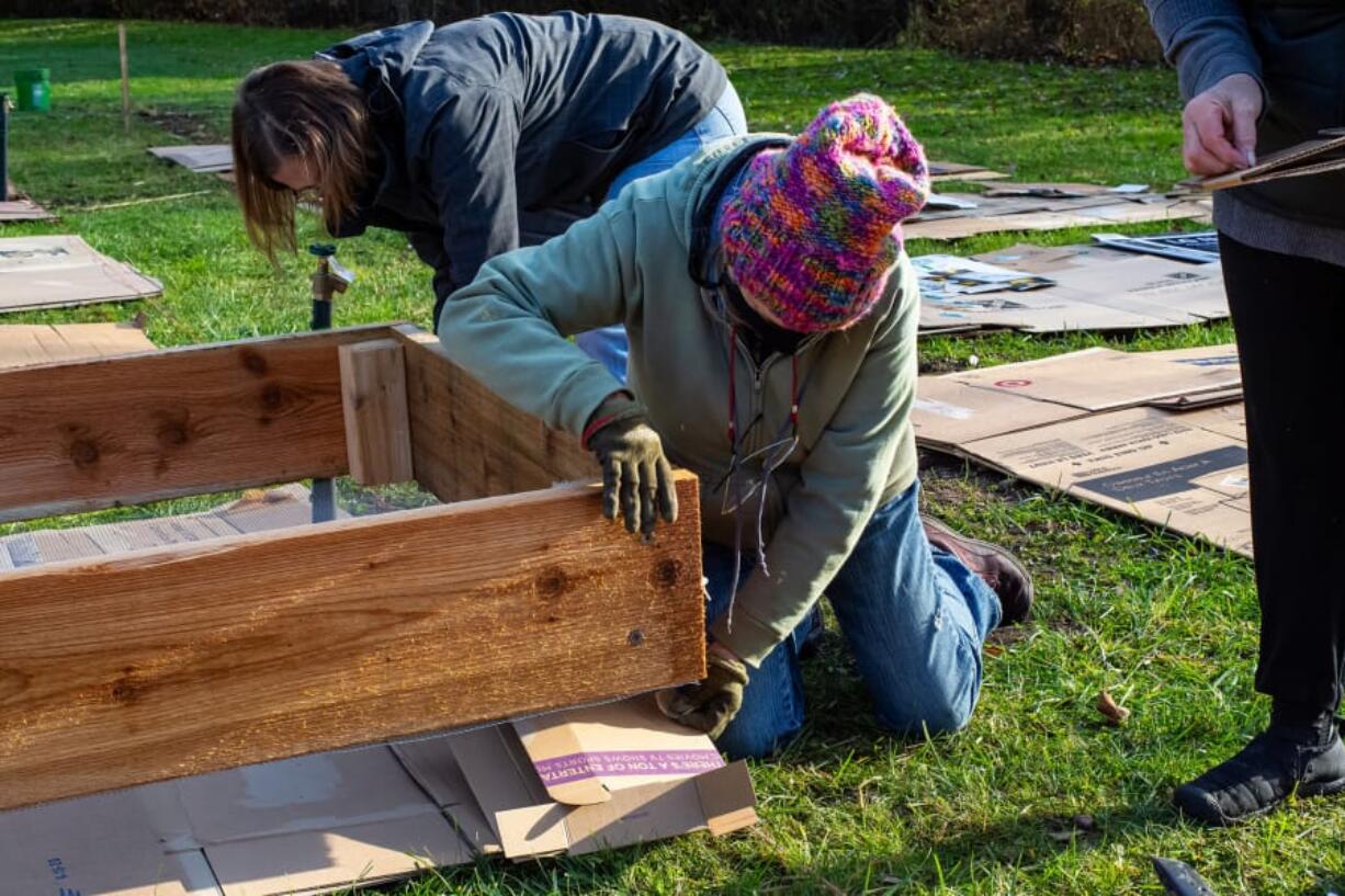 MAPLEWOOD: Volunteers Kitty Hibbs and Pat Wozniak adjust cardboard layers under raised beds.