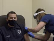 Firefighter and paramedic Josh Lawson, left, waits as system director Sara Williams applies a bandage after he received a COVID-19 vaccination at PeaceHealth Southwest Urgent Care in Vancouver. PeaceHealth has administered the vaccine to nearly 100 first responders from Clark and Cowlitz counties. The plan is to give roughly 200 first responders the first dose of the vaccine over the next couple weeks.