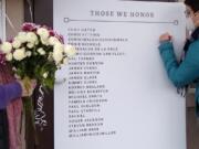 Laura Ellsworth, right, writes a message on a memorial board set up Friday at St. PaulÌs Lutheran Church in Vancouver. Ellsworth is with the Council for the Homeless, which helped set up the board with the names of the homeless from the community who died in 2020. On Monday night, the council held a virtual ceremony to remember the members of the community who died in 2020.