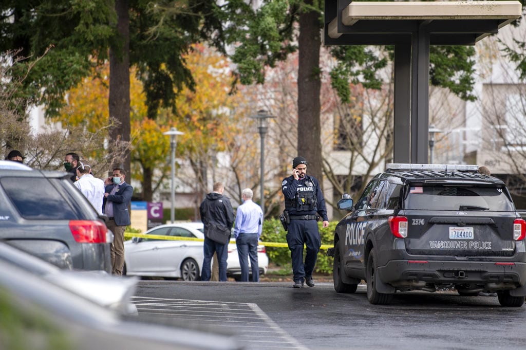 A police officer talks on his cell phone while officials congregate in front of a building where a shooting reportedly occurred on Tuesday, December 22, at the 505 building at the PeaceHealth Southwest Medical Center.