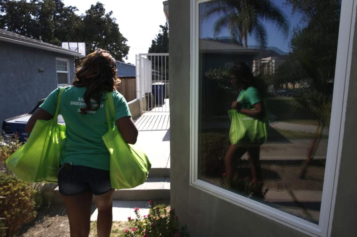 An Instacart shopper carries groceries. Shoppers say they earn less due to poor reviews CfO even when the bad ratings are no fault of their own.