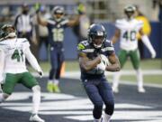 Seattle Seahawks wide receiver David Moore cradles the ball after catching a touchdown pass as New York Jets safety Matthias Farley (41) reacts behind during the second half of an NFL football game, Sunday, Dec. 13, 2020, in Seattle.