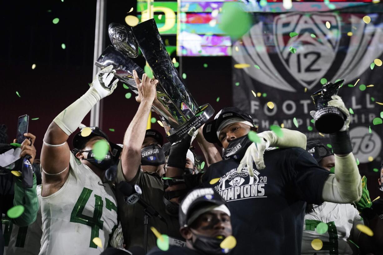 Oregon head coach Mario Cristobal, center, and defensive end Kayvon Thibodeaux, right, present their championship trophy and MVP trophy after winning the NCAA college football game for the Pac-12 Conference championship Friday, Dec 18, 2020, in Los Angeles. Oregon won 31-24.