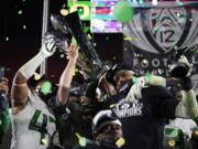 Oregon head coach Mario Cristobal, center, and defensive end Kayvon Thibodeaux, right, present their championship trophy and MVP trophy after winning the NCAA college football game for the Pac-12 Conference championship Friday, Dec 18, 2020, in Los Angeles. Oregon won 31-24.