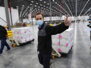 A worker gives a thumbs up while transporting boxes containing the Moderna COVID-19 vaccine to the loading dock for shipping at the McKesson distribution center in Olive Branch, Miss., Sunday, Dec. 20, 2020.