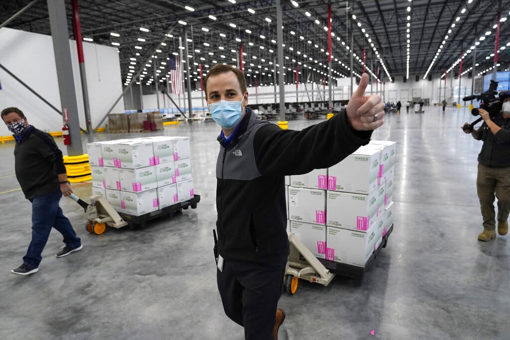 A worker gives a thumbs up while transporting boxes containing the Moderna COVID-19 vaccine to the loading dock for shipping at the McKesson distribution center in Olive Branch, Miss., Sunday, Dec. 20, 2020.