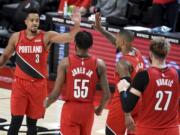 Portland Trail Blazers guard CJ McCollum, left, celebrates with teammates after hitting a shot to give the Blazers the lead late in overtime of an NBA basketball game against the Houston Rockets in Portland, Ore., Saturday, Dec. 26, 2020. The Blazers won 128-126.