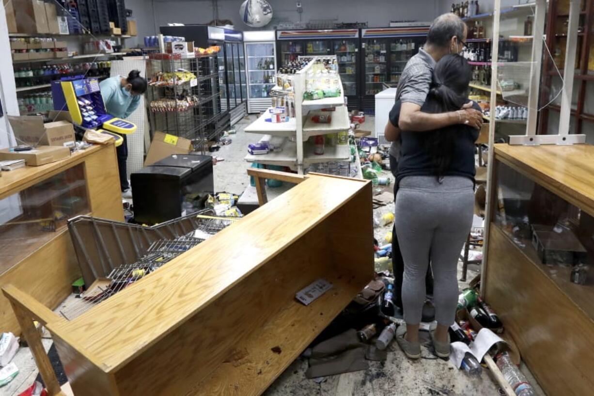 Yogi Dalal hugs his daughter Jigisha on Aug. 10 after she arrived at the family food and liquor store and as his other daughter Kajal, left, bows her head after the family business was vandalized in downtown Chicago.