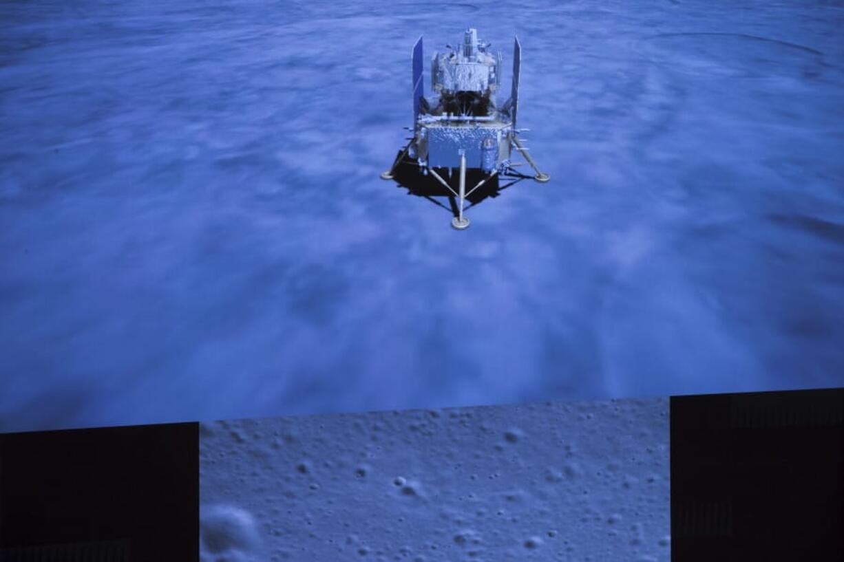 In this photo released by Xinhua News Agency, a screen shows the landed Chang&#039;e-5 spacecraft and a moon surface picture, below, taken by camera aboard Chang&#039;e-5 spacecraft during its landing process, at Beijing Aerospace Control Center (BACC) in Beijing on Tuesday, Dec. 1, 2020. A Chinese spacecraft landed on the moon Tuesday to bring back lunar rocks to Earth for the first time since the 1970s, the government announced.