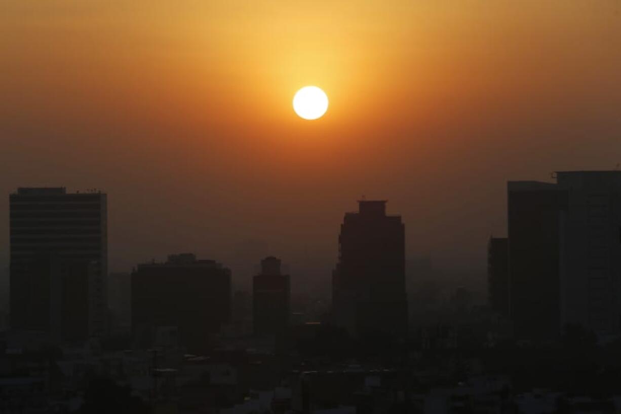 FILE - In this Thursday, Feb. 20, 2020 file photo, the sun rises amid smog during the dry season in Mexico City. Five years after a historic climate deal in Paris, world leaders are again meeting to increase their efforts to fight global warming.