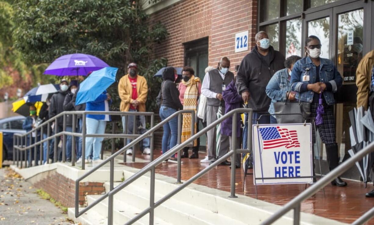 FILE - In this Monday, Dec. 14, 2020, file photo, people wait in line on the first day of advance voting for Georgia&#039;s Senate runoff election at the Bell Auditorium in Augusta, Ga. A federal judge on Monday, Dec. 28, 2020, has ordered local election officials in Georgia to allow voting by more than 4,000 people whose eligibility had been challenged ahead of the U.S. Senate runoff elections next week. U.S. District Court Judge Leslie Abrams Gardner said that denying so many voters access to the ballot so close to an election would likely violate the National Voter Registration Act.