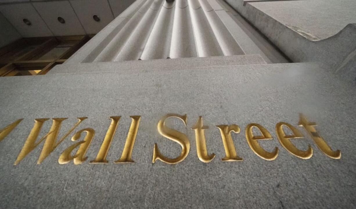 FILE - In this Nov. 5, 2020 file photo, a sign for Wall Street is carved in the side of a building.   Stocks rose on Wall Street, Wednesday, Dec. 30, putting the market back on a positive footing following a modest pullback the day before.